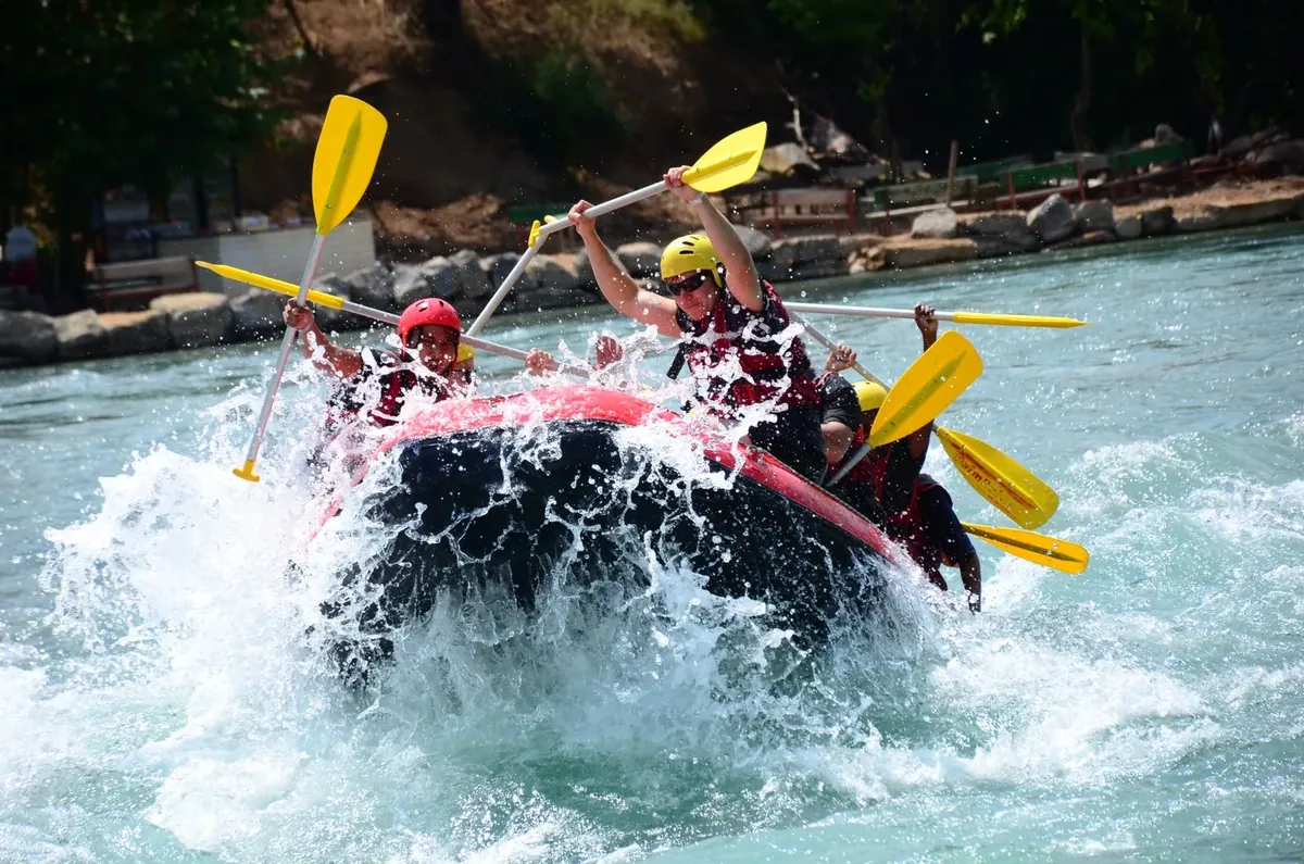 Rafting botunda küreklerini kaldıran tur grubu